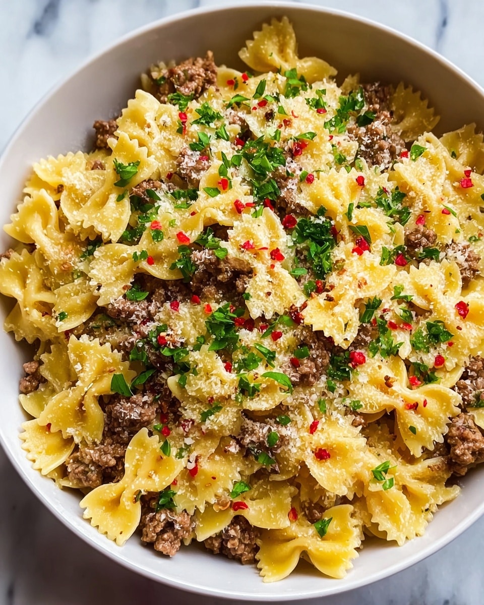 A close-up view of a white bowl filled with a pasta dish composed of three layers: the bottom and main layer is yellow bow-tie pasta with a slightly glossy texture, mixed evenly with small crumbles of light brown cooked ground beef, creating a speckled look; the second layer is a generous sprinkle of fine, pale grated cheese spread evenly across the pasta and beef; the top layer is a scattering of small, fresh green parsley pieces and tiny red chili flakes, adding bright color contrast on top. The bowl is placed on a white marbled surface. photo taken with an iphone --ar 4:5 --v 7