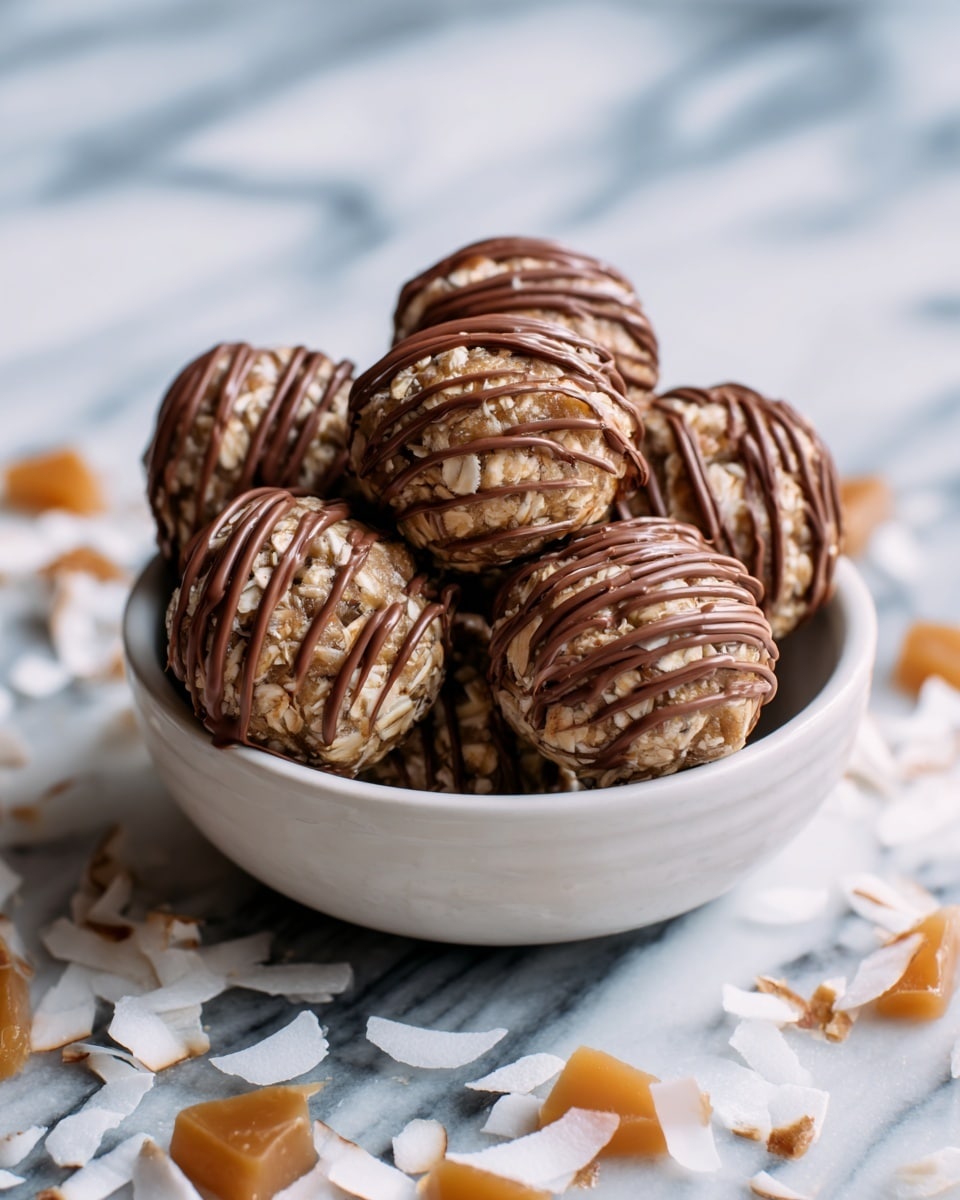This image shows a white bowl filled with seven round oat balls, each covered with visible oatmeal texture and drizzled with smooth milk chocolate in thin stripes. The round shapes are stacked neatly, creating a small pile, and the bowl rests on a surface with a white marbled texture. Around the bowl, there are scattered pieces of white coconut flakes and bits of caramel-colored candy adding contrast. The overall look is natural and inviting with a focus on the texture of the oat balls and the shine of the chocolate drizzle. Photo taken with an iphone --ar 4:5 --v 7