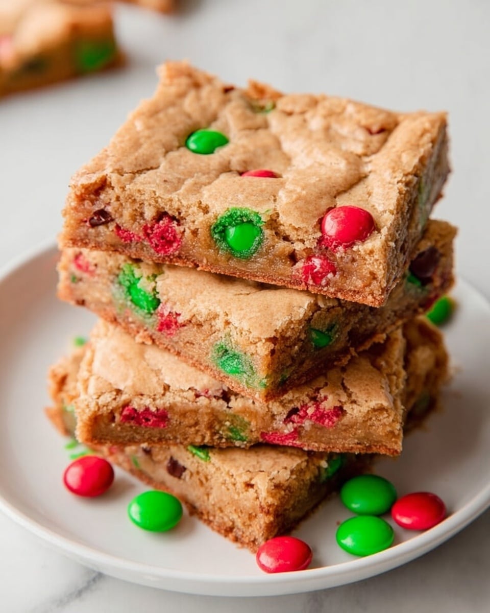 A stack of five square cookie bars sits centered on a white plate, each bar showing a light golden-brown top layer with cracks and colorful red and green candy pieces embedded throughout. The edges of the bars are slightly crumbly, revealing a soft, chewy inside dotted with more candy pieces. The candies add small round pops of bright red and green on every bar, contrasting with the warm beige dough. The plate rests on a white marbled surface, with a few stray red and green candies next to the stack. Photo taken with an iphone --ar 4:5 --v 7