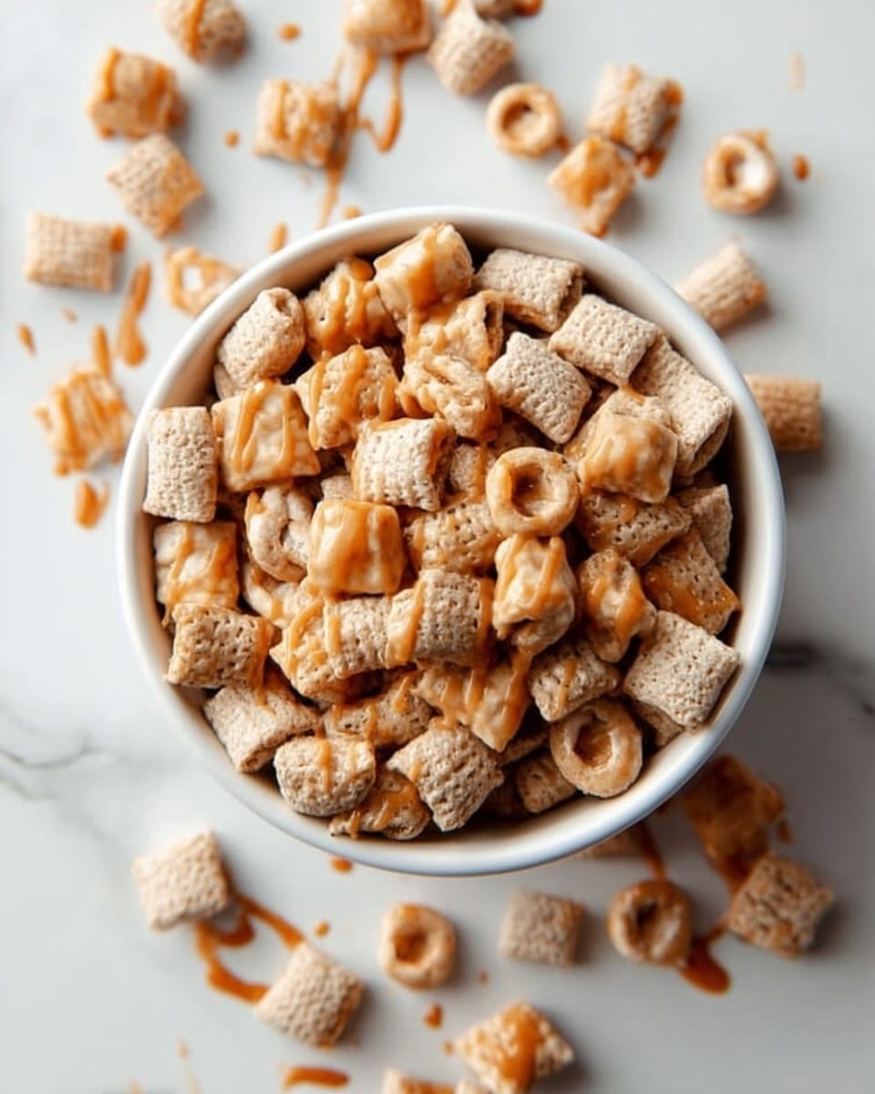 A white bowl filled with a mix of light brown square and small round cereals, drizzled with a shiny caramel-colored sauce on top. Some pieces of cereal are also scattered outside the bowl on a white marbled surface. The cereals have a rough, crunchy texture, and the caramel drizzle adds a smooth, glossy contrast. photo taken with an iphone --ar 4:5 --v 7