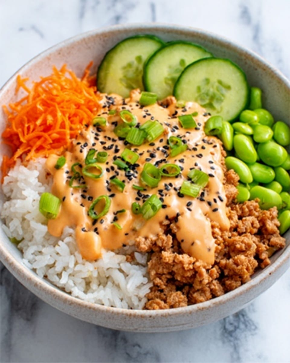 The image shows a white bowl filled with four main layers. At the bottom is a layer of white rice with a soft, fluffy texture. On top of the rice, to the right, is a chunky, light brown minced meat layer covered partially by an orange creamy sauce with a smooth texture. At the back of the bowl, there are thin, bright green cucumber slices arranged in a line, next to a small pile of shredded, bright orange carrots. The front of the bowl has a cluster of green edamame beans, and the top of the dish is sprinkled with black and white sesame seeds and small green onion pieces. The bowl sits on a surface with a white marbled texture. photo taken with an iphone --ar 4:5 --v 7