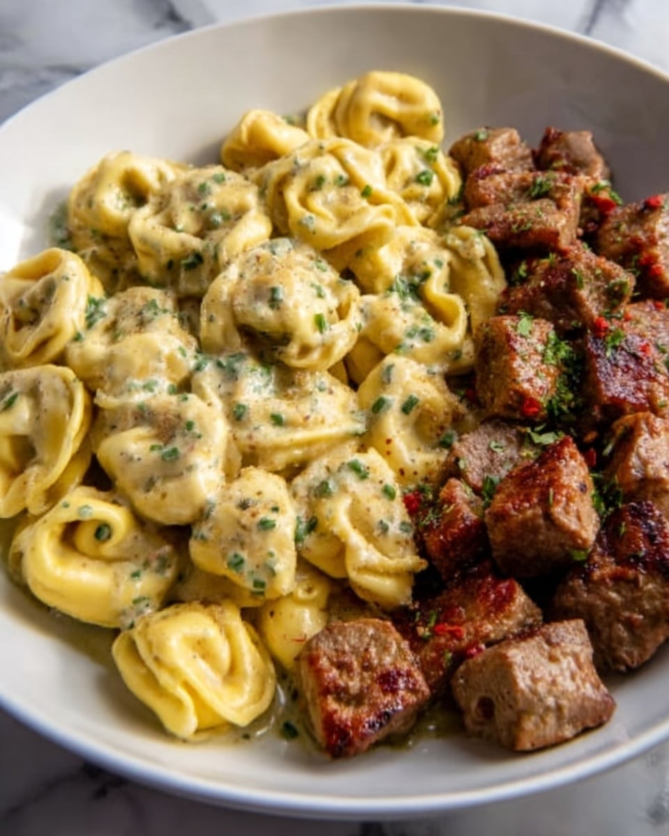 The dish features a white plate filled with two sections: on the left, there are golden-yellow tortellini pasta pieces coated in a creamy sauce with small green herb sprinkles scattered on top, their smooth, curved shapes tightly packed together; on the right, there are bite-sized brown meat chunks with a slightly crispy texture and some herb flakes, arranged in a neat pile. The contrast between the creamy, soft pasta and the firm, browned meat pieces is clear, all placed on a surface with a white marbled texture. Photo taken with an iphone --ar 4:5 --v 7